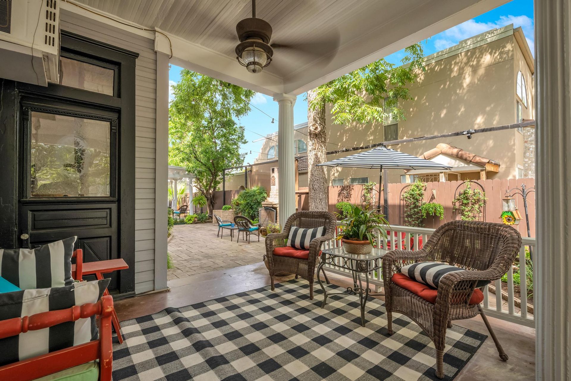 A porch with chairs , a table and a ceiling fan.