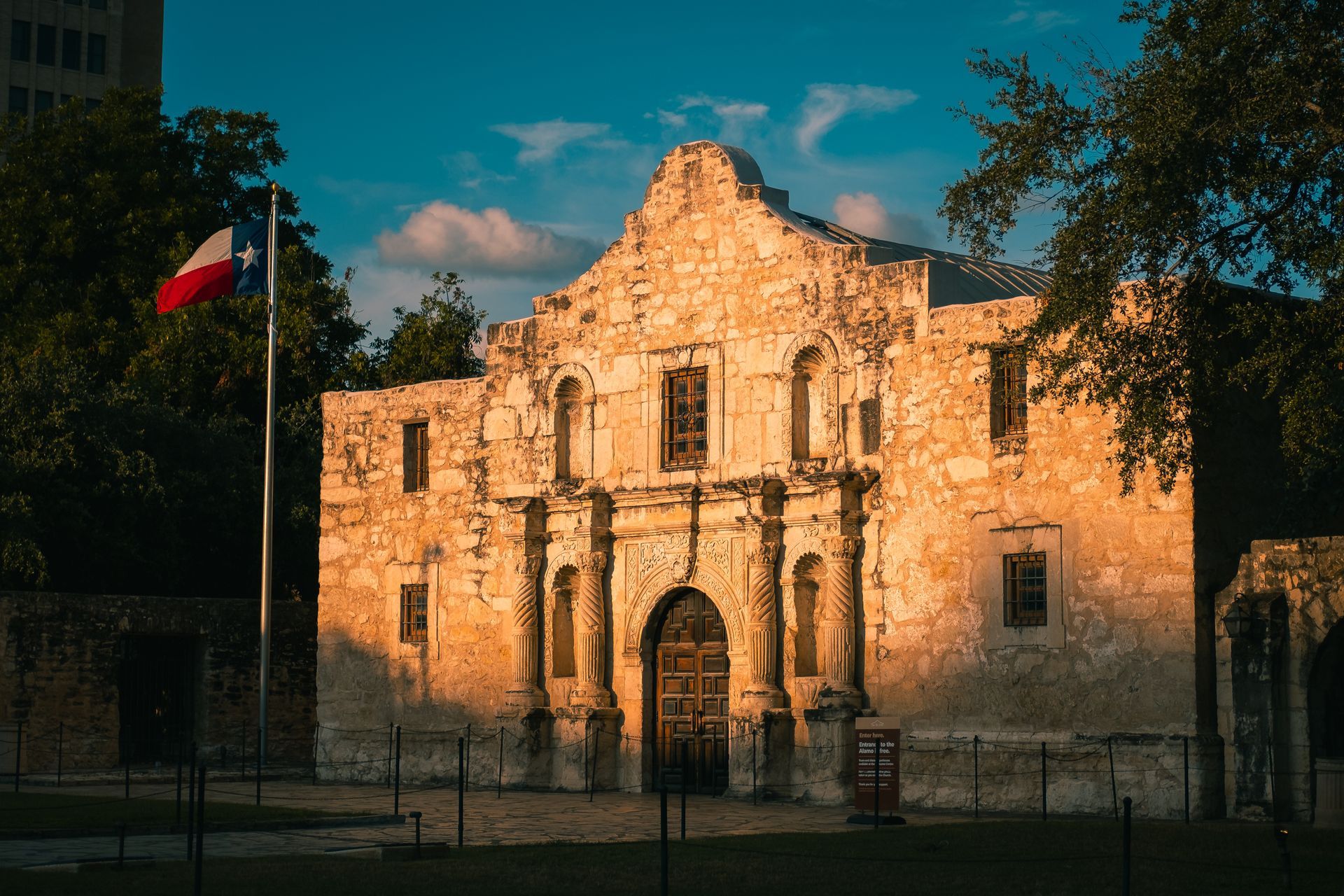 A large stone building with a texas flag flying in front of it.