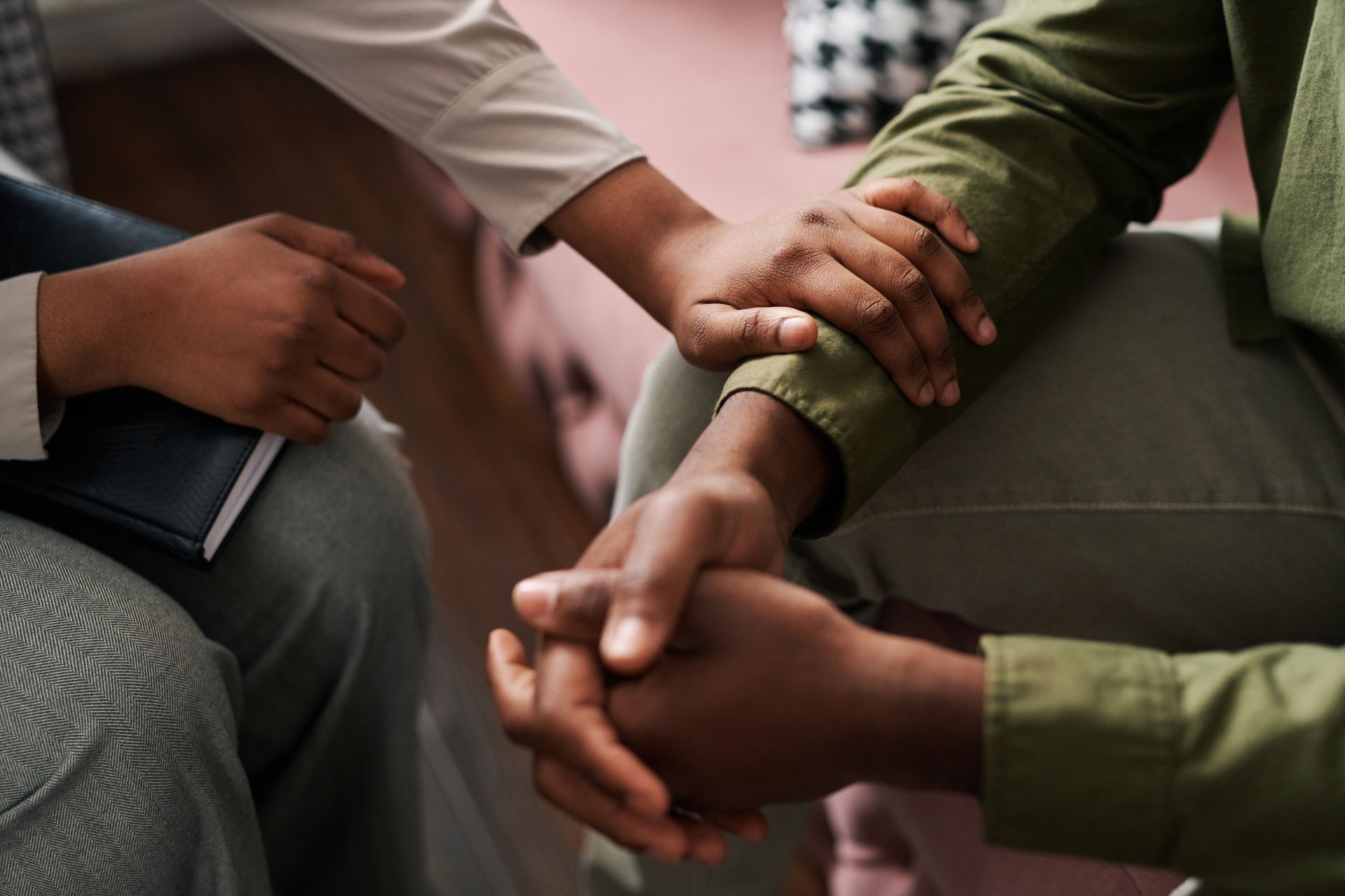 Two people sit together, holding hands to show comfort and connection. Two people sit together, holding hands to show comfort and connection.
