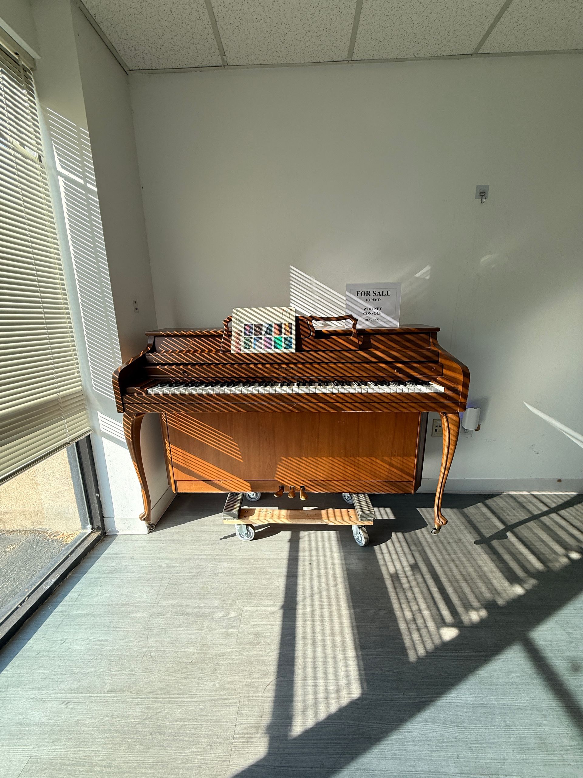 Wicker table in a sunlit corner by a window, with papers and a small sign on top.