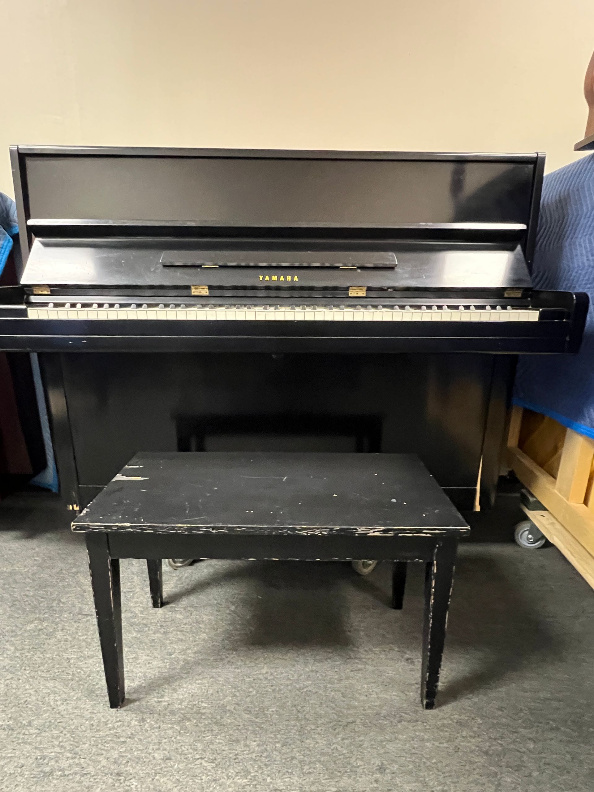 Upright piano with black finish and matching bench.