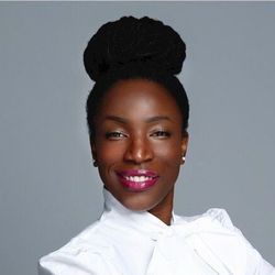 A woman with a bun on her head is wearing a white shirt and smiling.