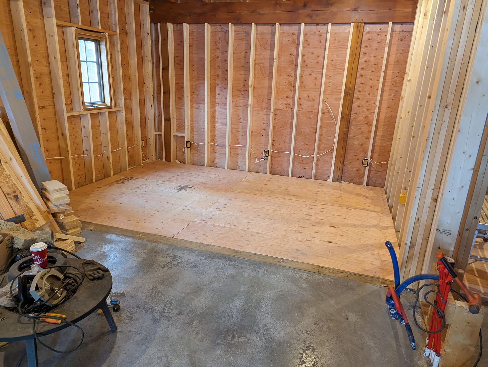 Interior construction: wood-framed walls, curved floor, insulation, plumbing, window, unfinished space.