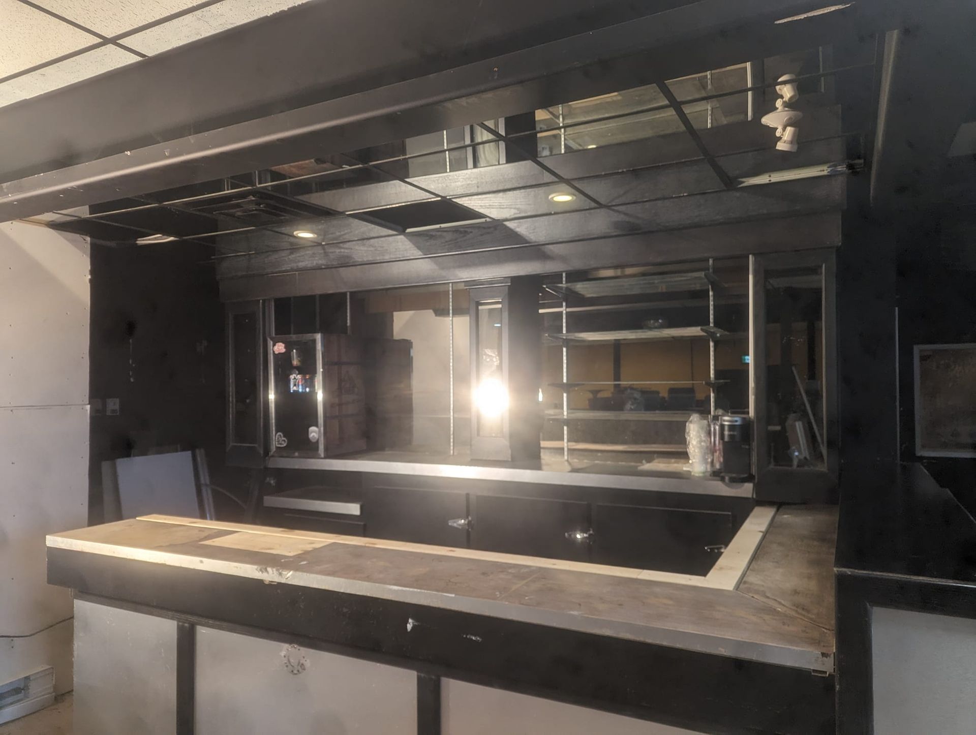 Interior shot of an empty bar, a dark structure with a countertop and shelves.