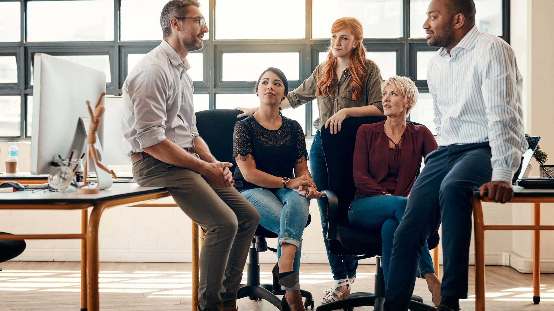 A group of people are sitting around a table in an office having a meeting.