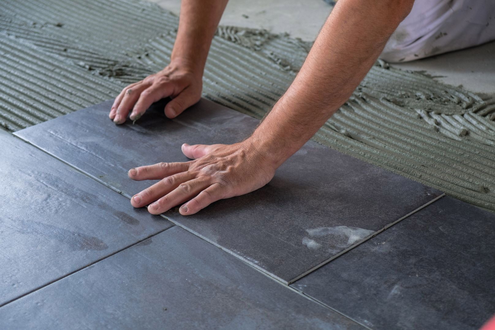 Laying bathroom floor tiles during plumbing installation preparation