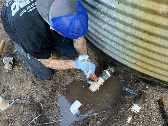 Emergency plumber fixing burst pipe leak outside home in Orange County