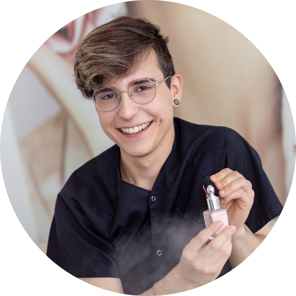 Ein junger Mann mit Brille hält eine Parfümflasche in der Hand