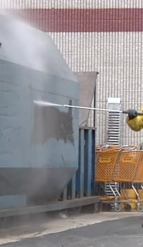 A person is using a high pressure washer to clean a building.