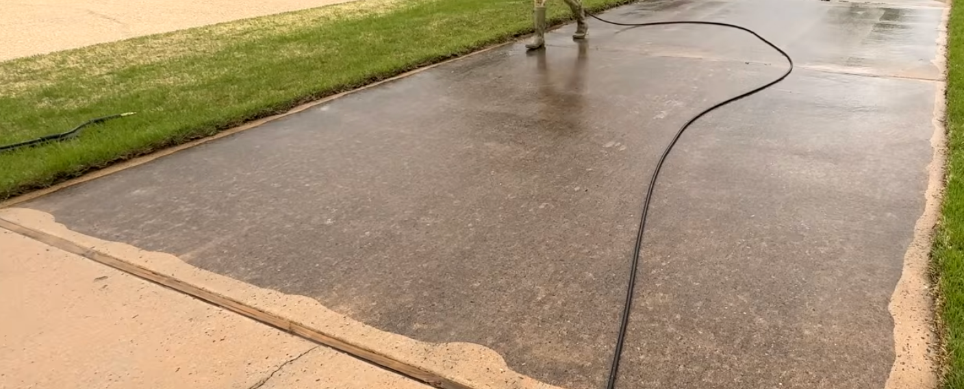 A person is using a pressure washer to clean a sidewalk.
