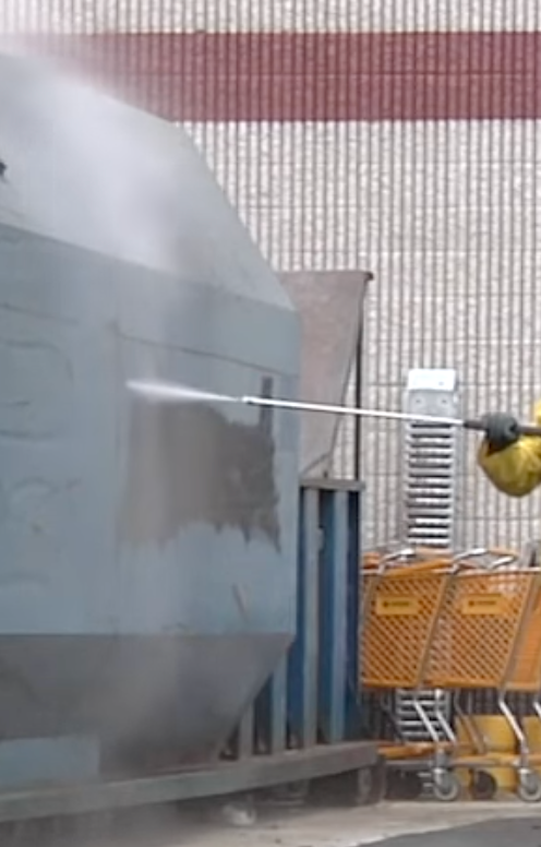 Pressure washing graffiti off concrete wall.