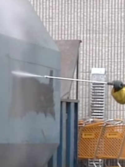 An expert is cleaning a wall with a high pressure washer.
