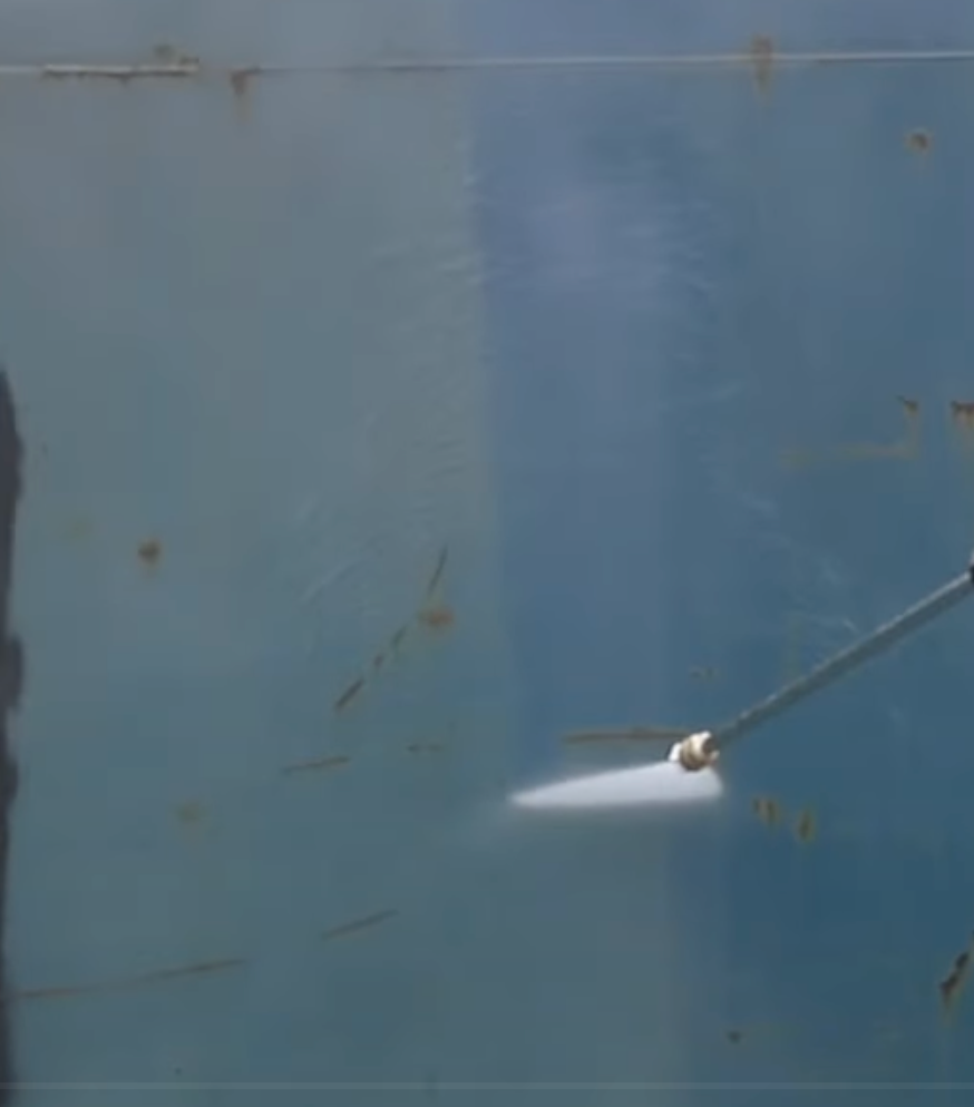 A hose is spraying water on a blue wall oh the house.