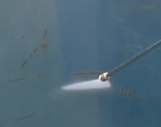 A power washer spraying a blue surface, creating a bright white streak.