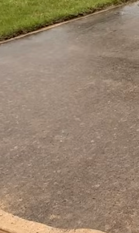 Wet asphalt pavement being pressured washed in Ragland.