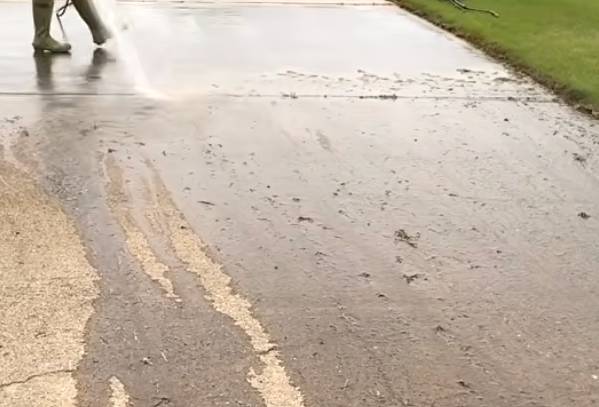A person is cleaning a house using a pressure washer.