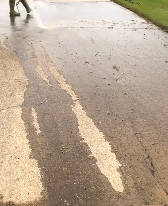 A person is cleaning a driveway using a pressure washer.
