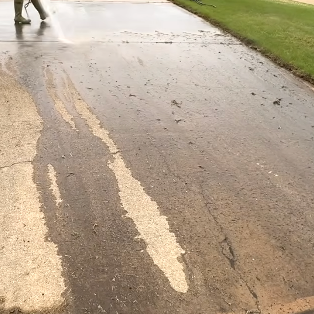 A person is cleaning a side walk with a pressure washer.