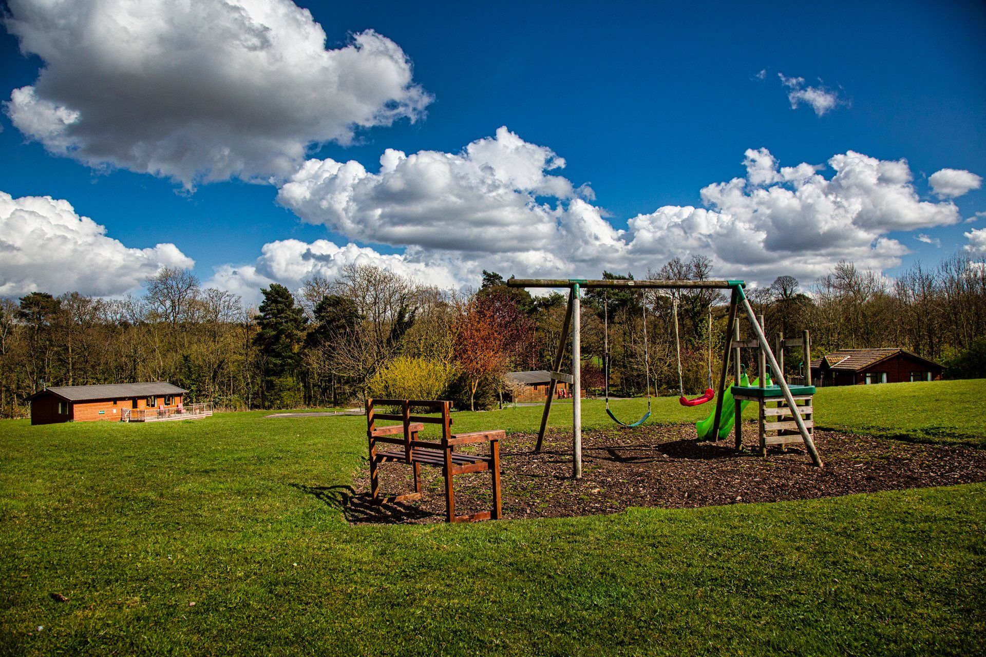 A playground with swings and a slide in a grassy field.