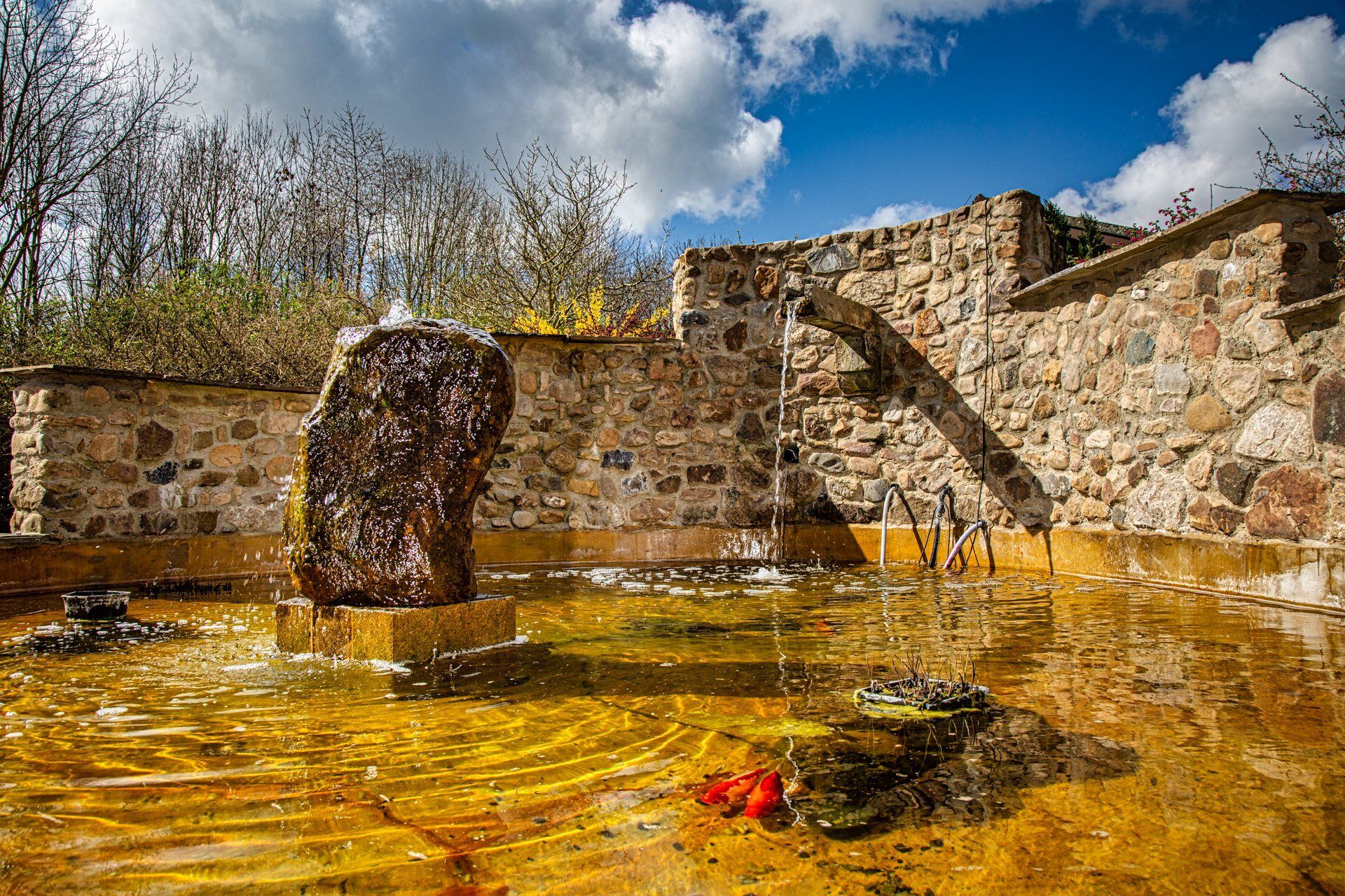 There is a fountain in the middle of a stone wall.