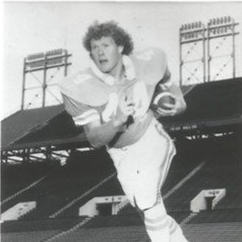 A black and white photo of a football player running with the ball.
