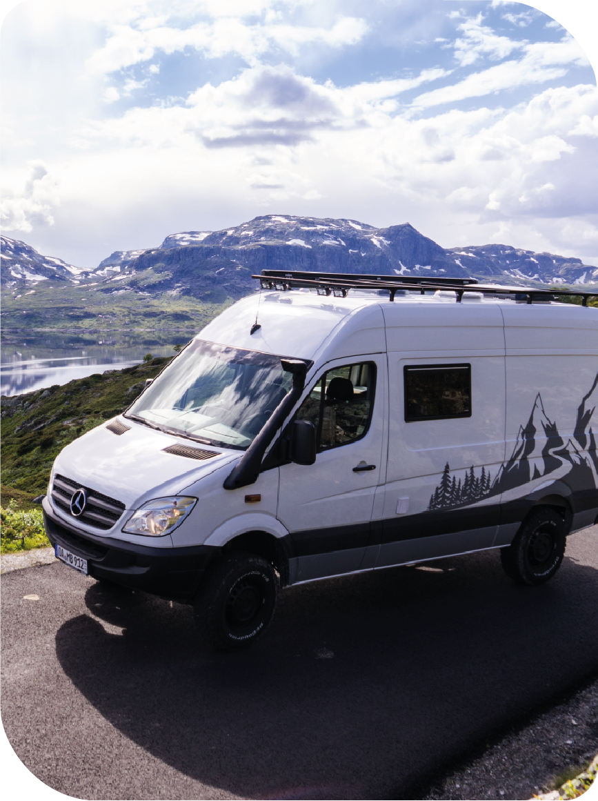 Ein weißer Lieferwagen steht am Straßenrand mit Bergen im Hintergrund