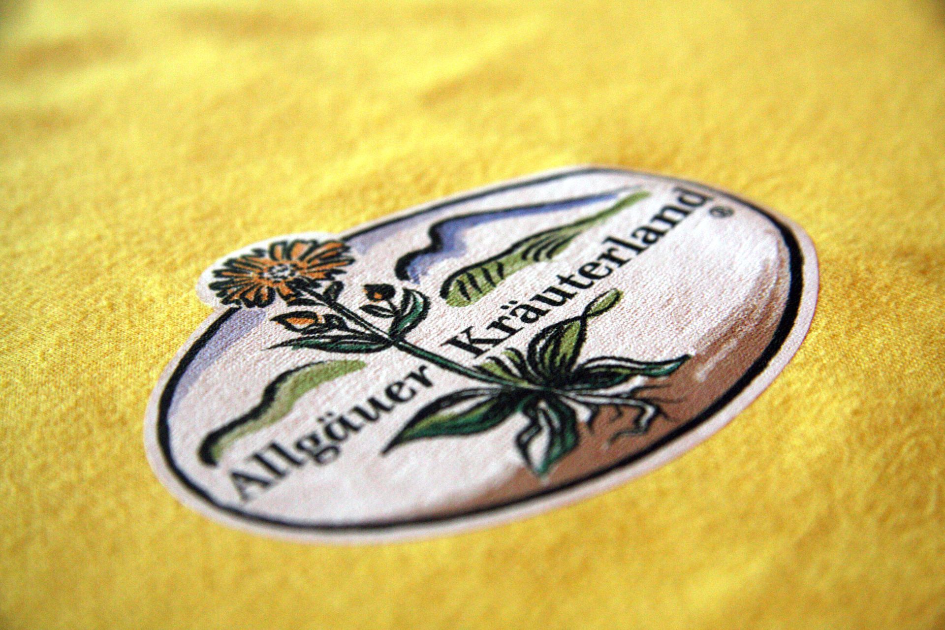 Logo des Allgäuer Kräuterland auf gelbem Stoff