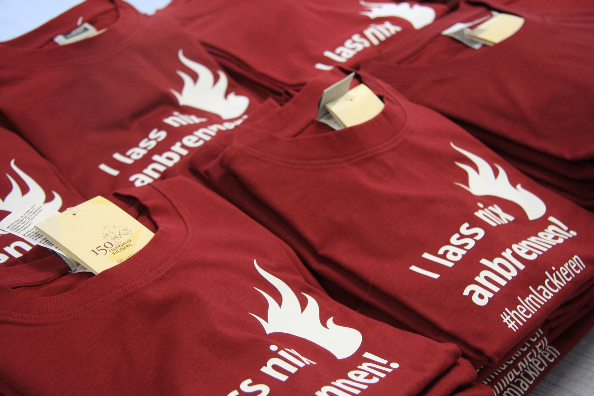 Ein Stapel roter T-Shirts mit der Aufschrift „I lass nix anbrennen“