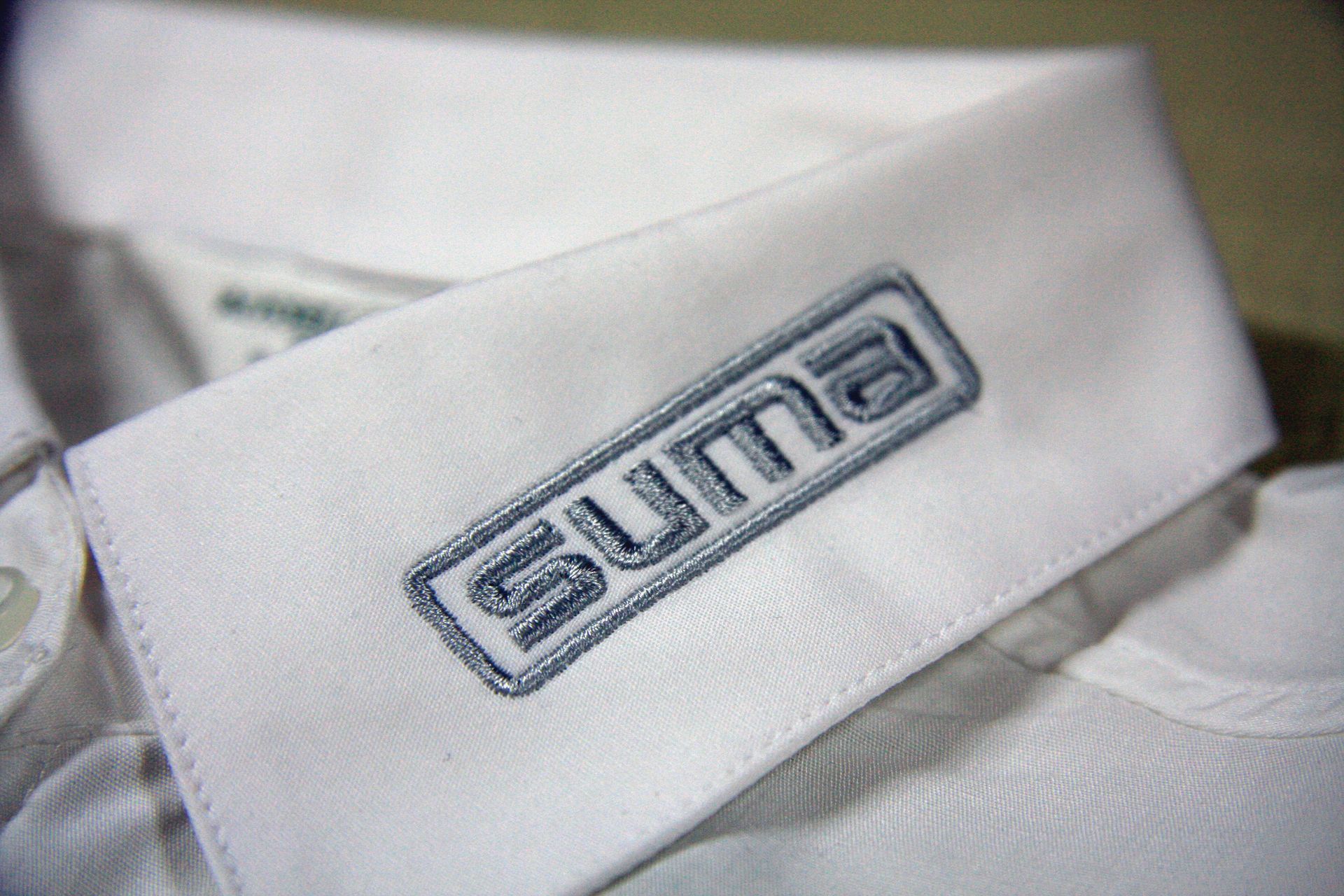 Ein weißes Hemd mit dem Wort Suma auf dem Kragen gestickt