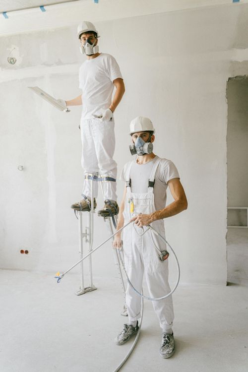 Two men wearing gas masks are standing next to each other in a room.