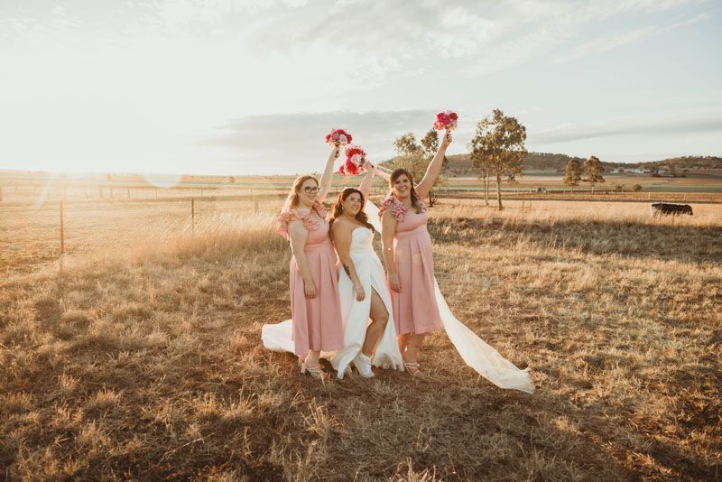 A bride and her bridesmaids are posing for a picture in a field.