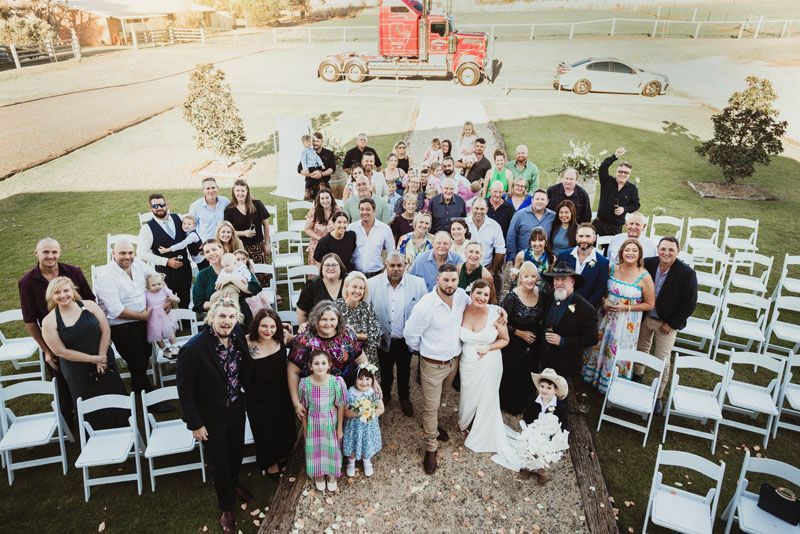 A large group of people are posing for a picture at a wedding outside Aberfeldy Barn