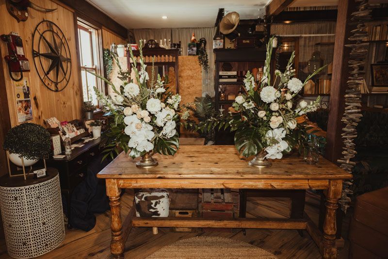 A wooden table with two vases of flowers on it in a room.