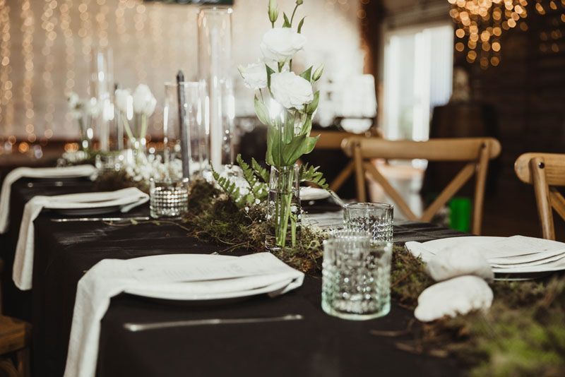 A table set for a wedding reception with plates , napkins , glasses and vases.