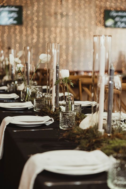 A table set for a wedding reception with plates , candles , and vases.