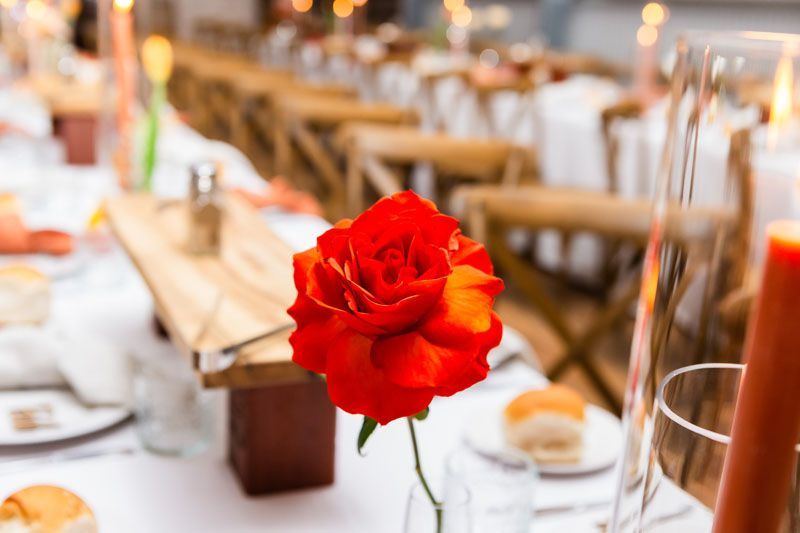 A red rose is in a vase on a table.