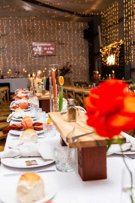A long table with plates , utensils , and flowers on it.