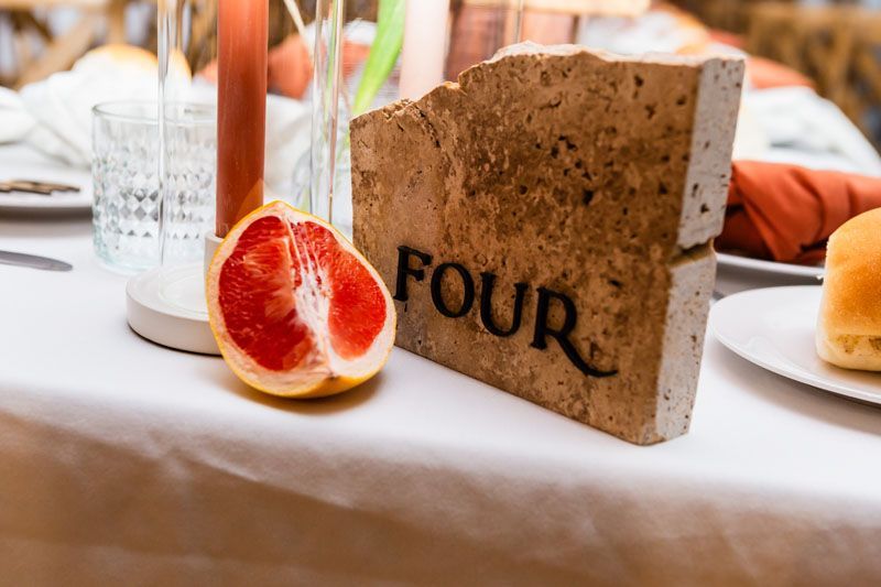 A table with a slice of grapefruit and a brick that says four on it.