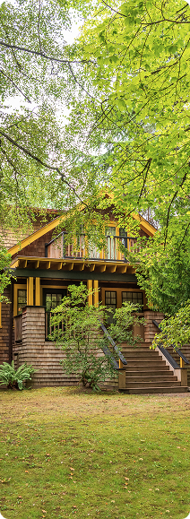 A yellow van is parked on the side of the road in front of a house.