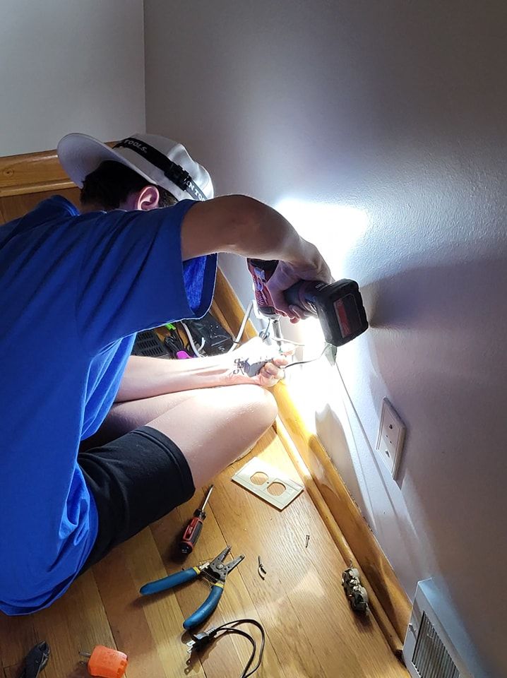 A man is kneeling on the floor using a drill.