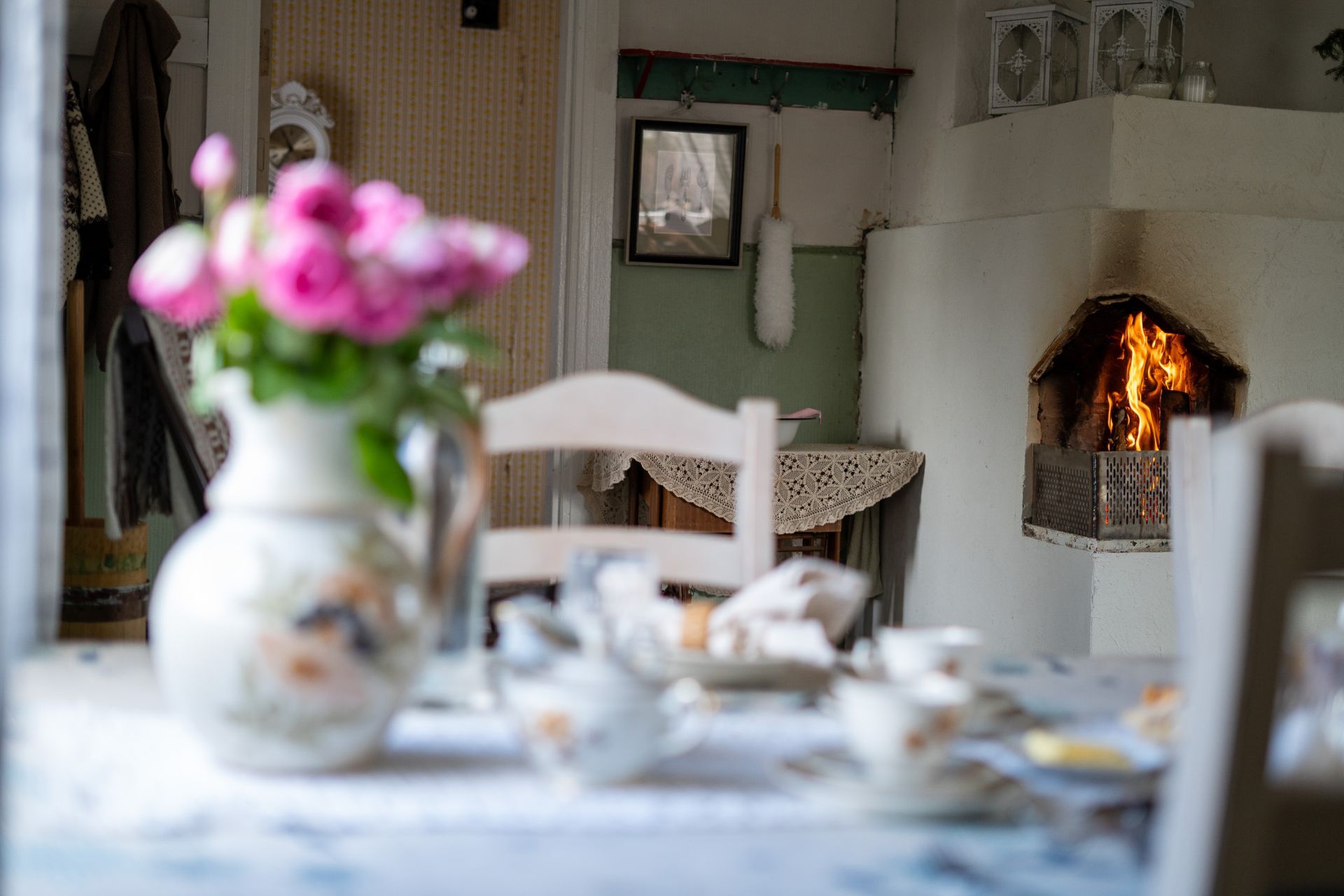 Table set with flowers and traditional Finnish food in an old house with fire in stove