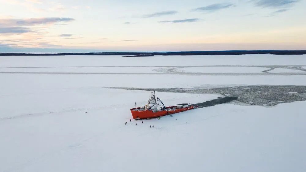 Polar Explorer ice breaker in the middle of icy sea, people walking on sea ice.