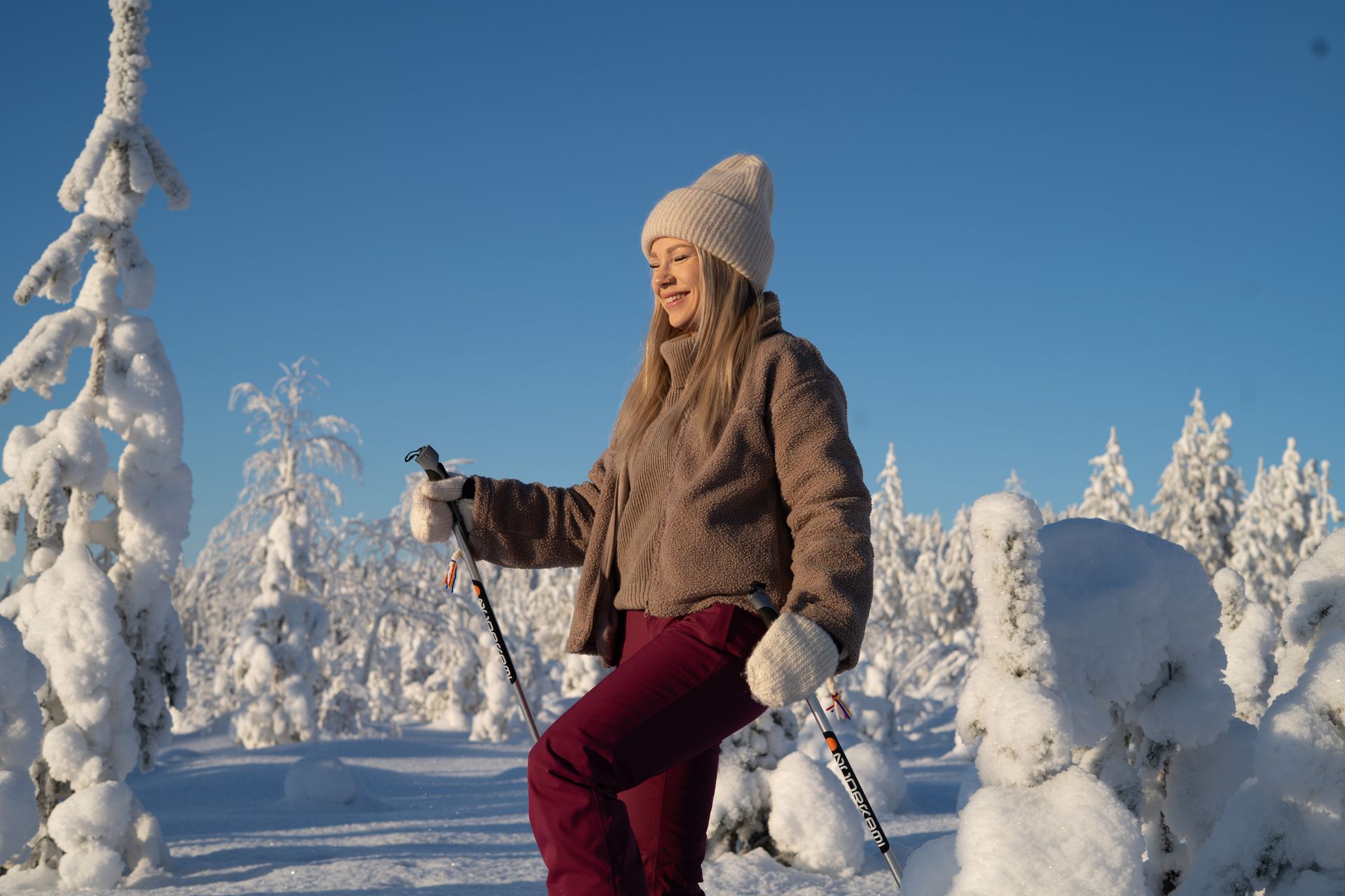 Woman snowshoeing in snowy open landscape.