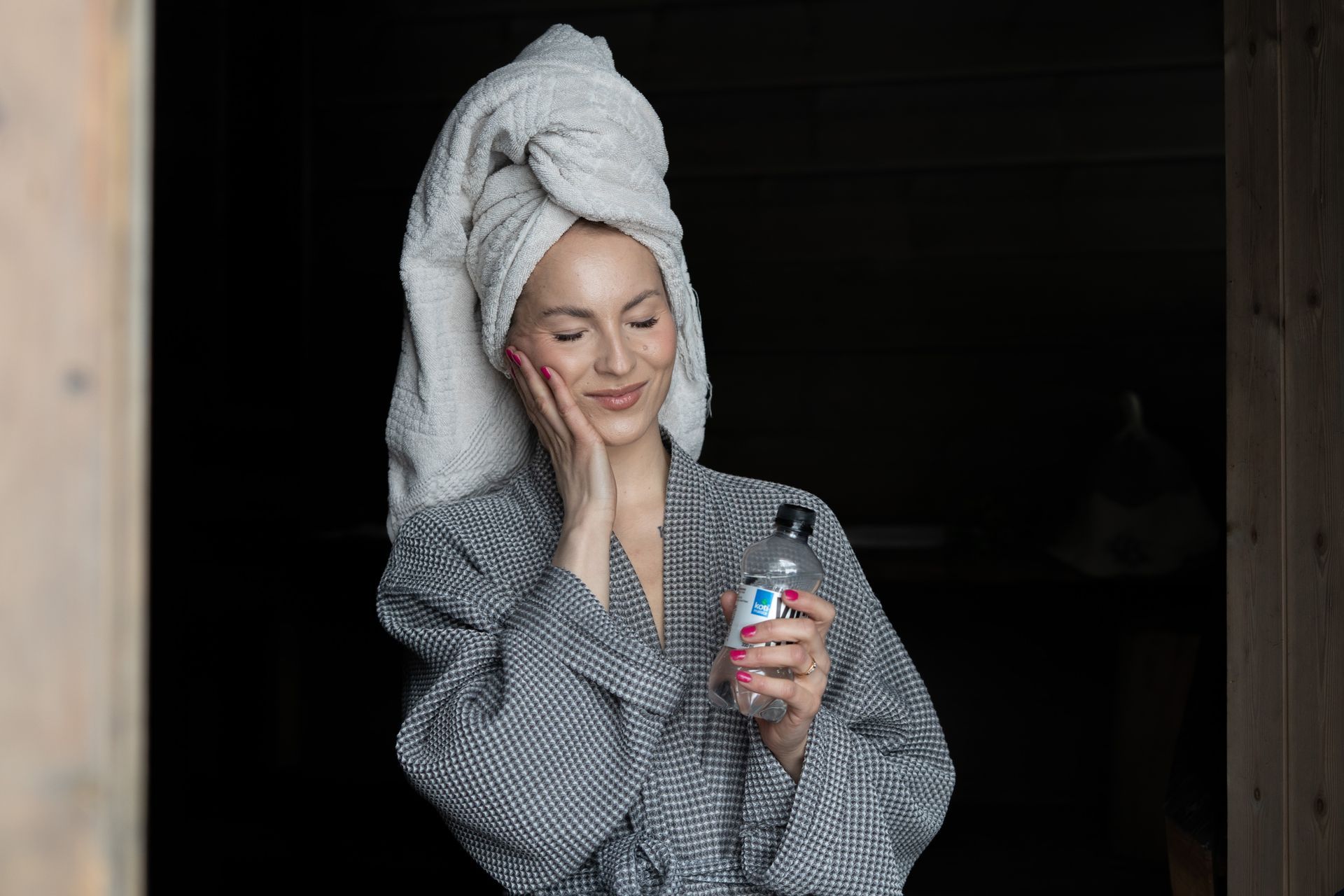 Woman enjoying sauna in bathrobe and towel in her hair