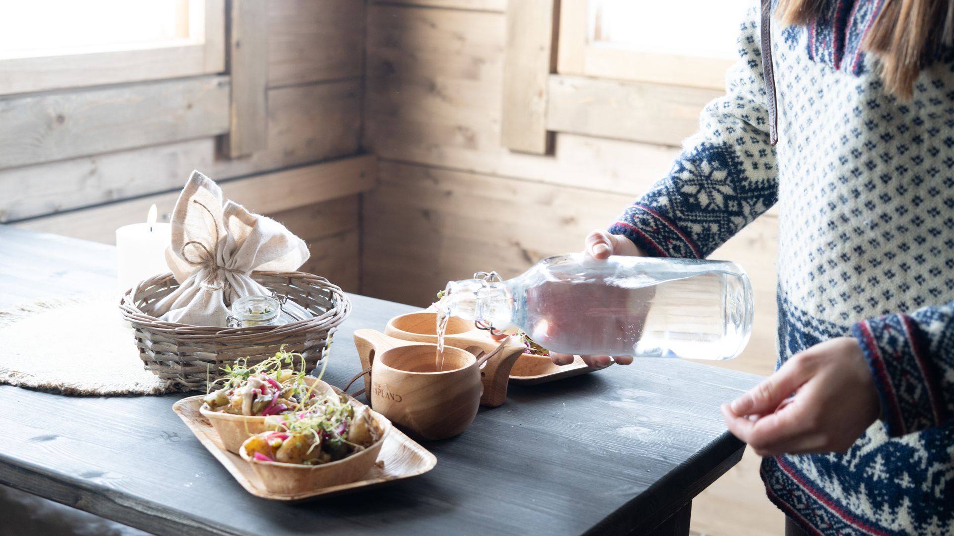 Woman serving table with kuksa mugs and potato boats