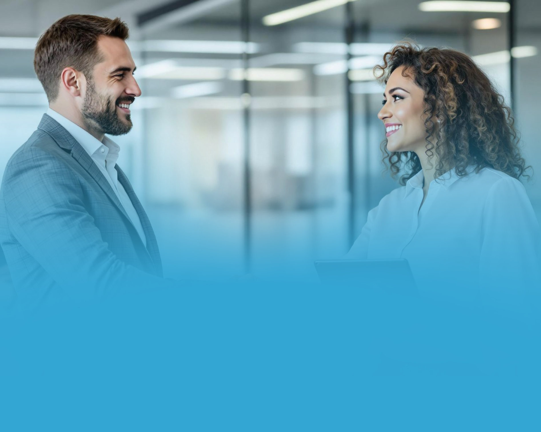 Homem e mulher em trajes profissionais sorrindo e conversando em um ambiente de escritório.
