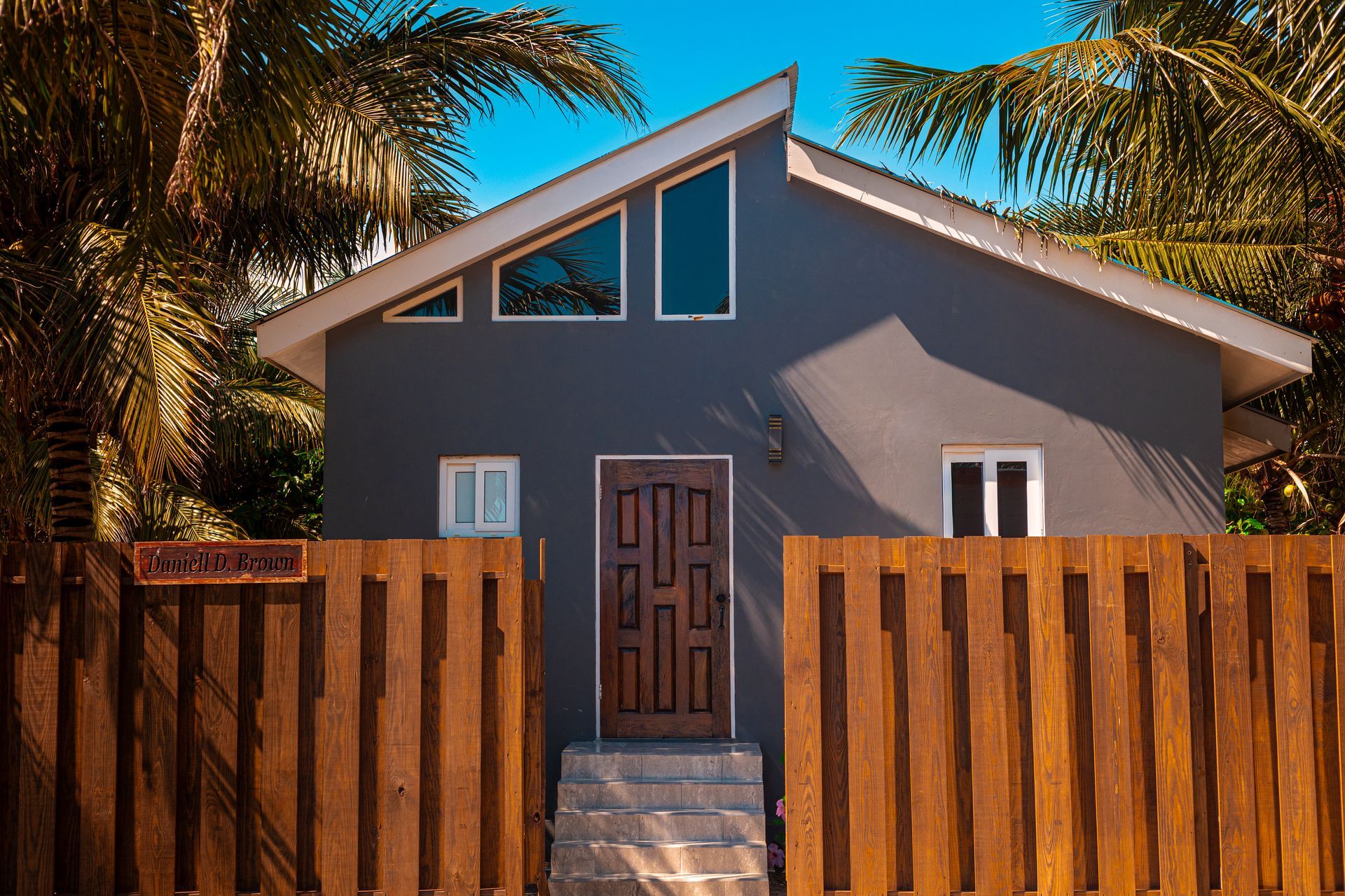 A light blue living room with a long white couch, large windows, and a dining area in the background.