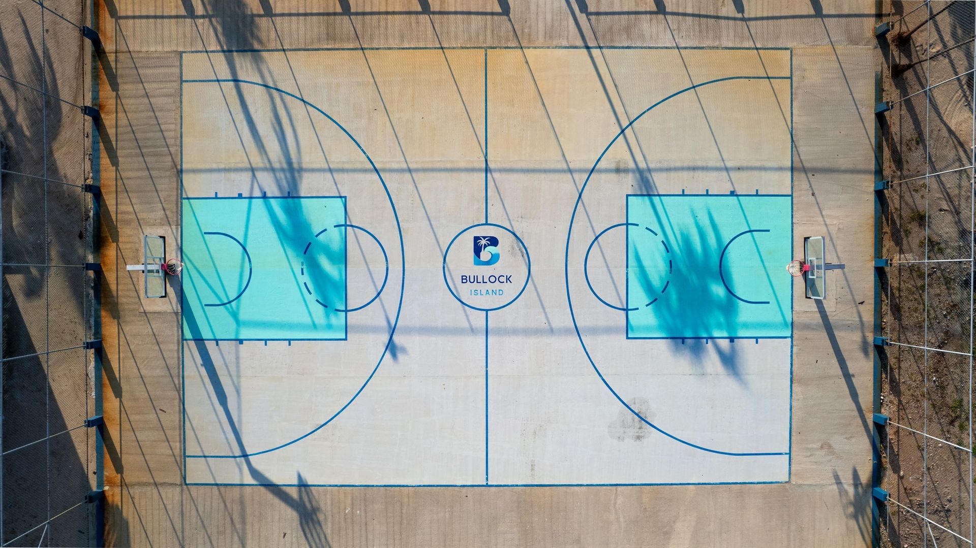Barbell on the floor of a dimly lit gym. Rope, blue bucket, and closed doors in the background.