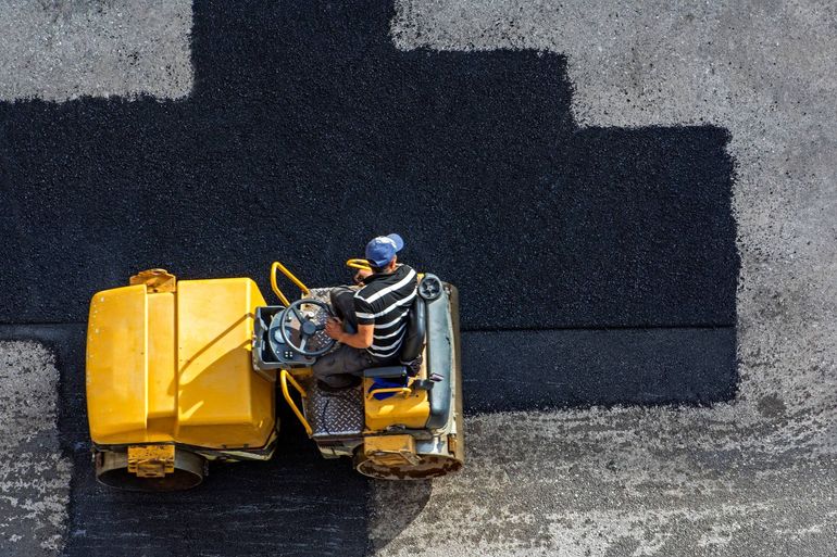 a man is driving a yellow roller on a road