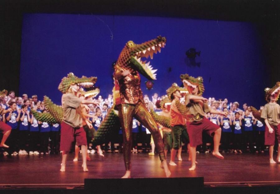 A group of people dressed as alligators are dancing on a stage